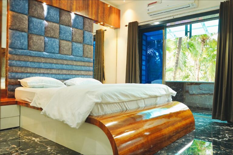 Megh Villa, Alibag: Bedroom with a padded headboard and doors to a balcony
