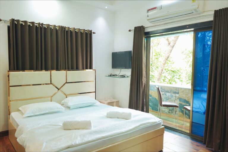 Megh Villa, Alibag: Bedroom with a wall TV and a balcony