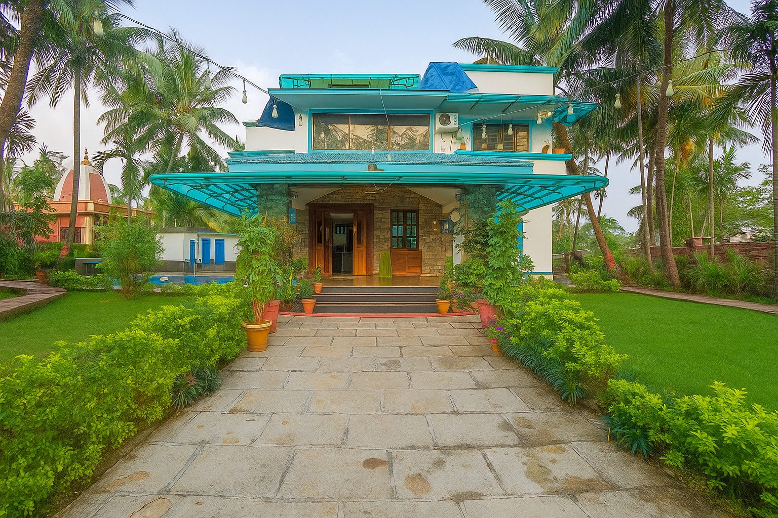 Megh Villa, a white two-storey villa with teal canopies at the end of a stone path between clipped hedges and coconut palms near Alibag